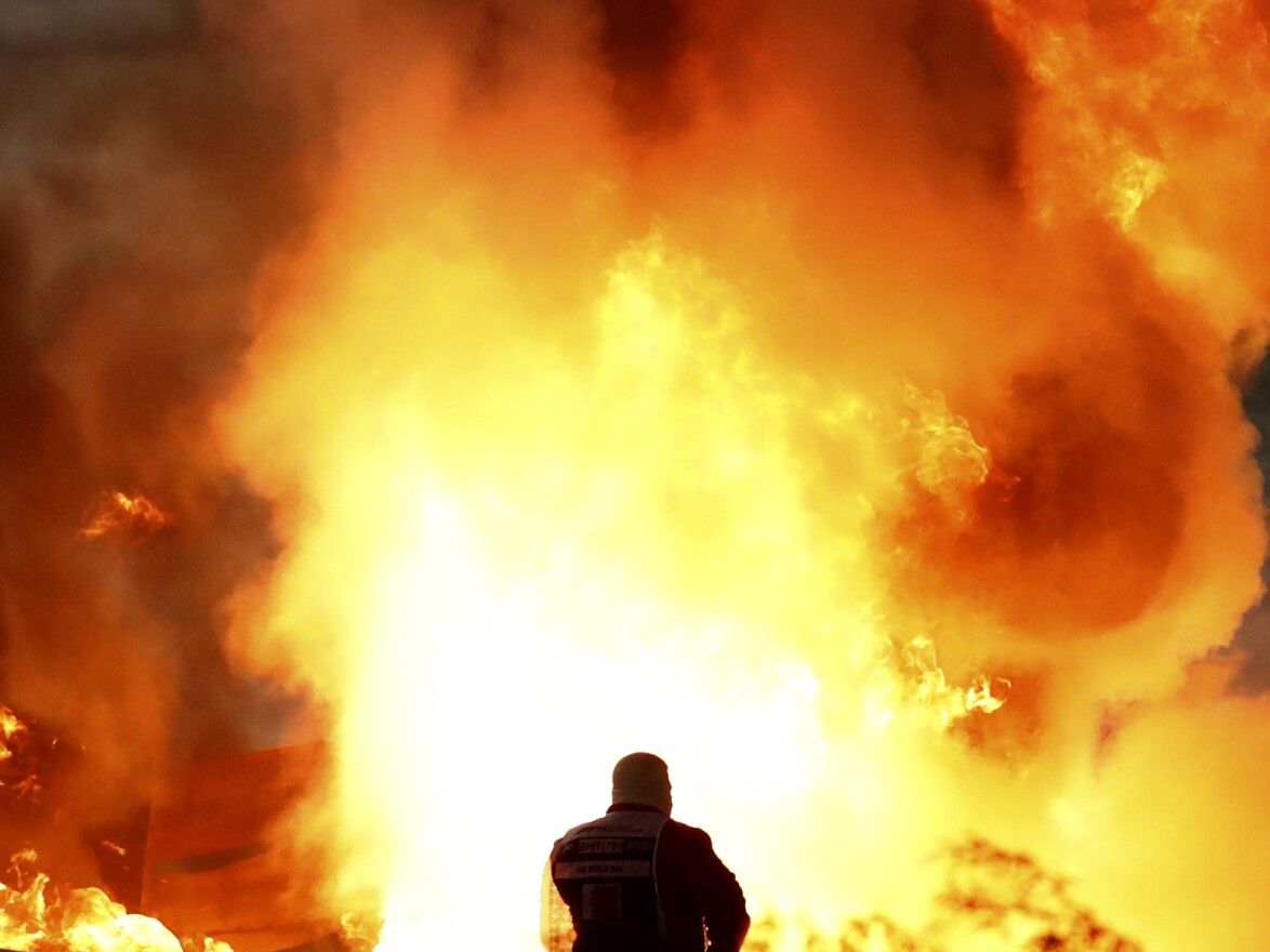 Staff extinguish flames from Haas driver Romain Grosjean of France's car after a crash during the Formula One race in Bahrain International Circuit in Sakhir, Bahrain, Sunday.